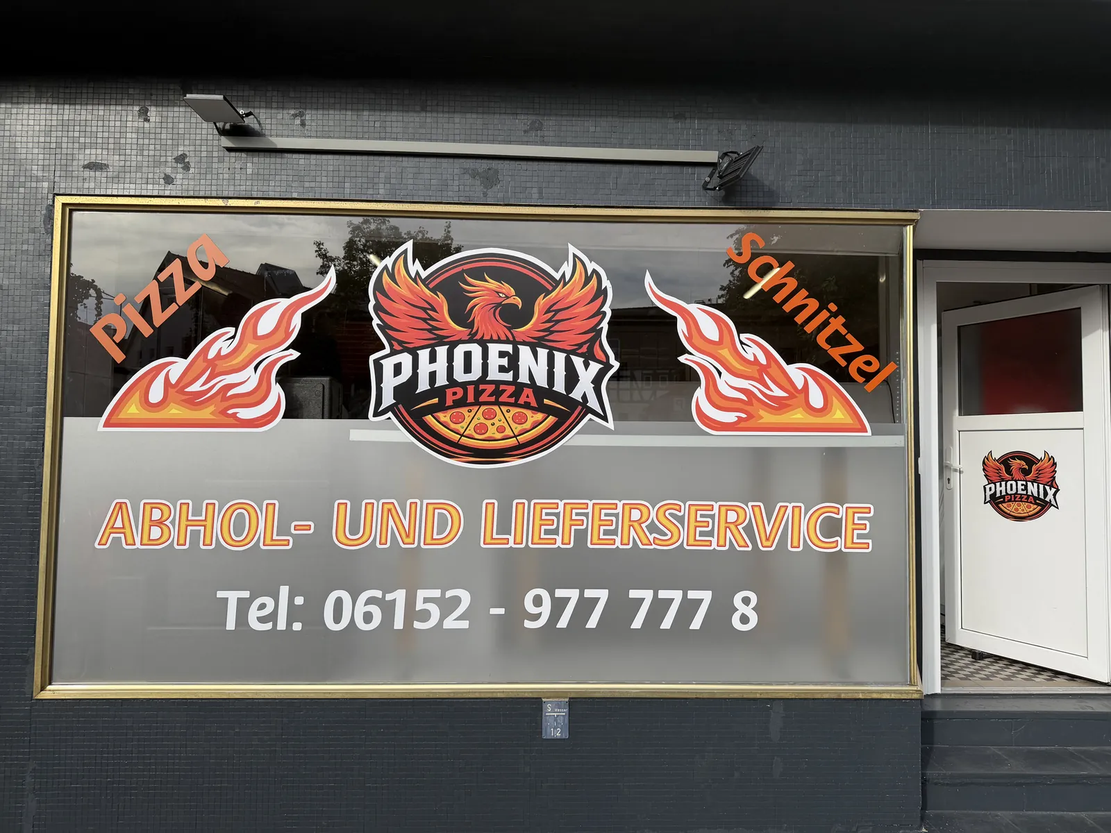 Ladenfront mit Logo im Schaufenster: Abhol- und Lieferservice, Pizza und Schnitzel